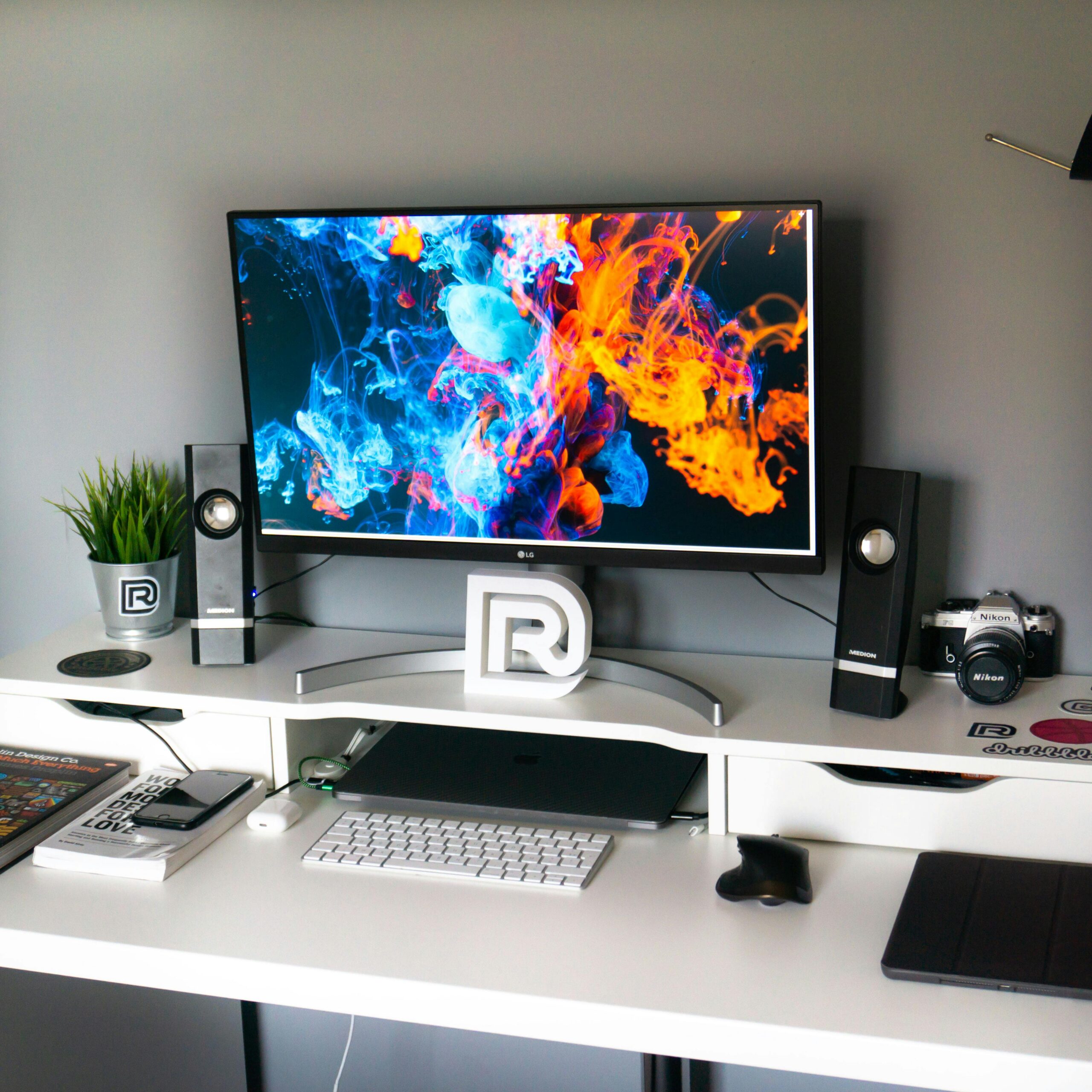 A sleek office setup with a vibrant widescreen monitor displaying colorful artwork.